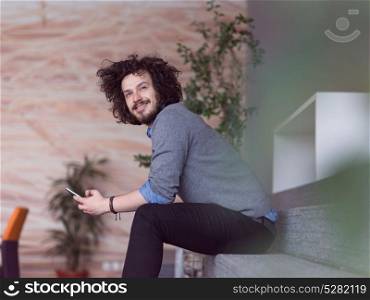 Young casual businessman holding smartphone in the startup office
