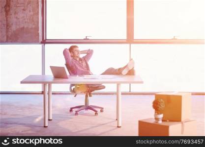 young casual businessman taking a break on construction site while checking documents and business workflow using laptop computer with sunlight through the windows during moving in at new startup office