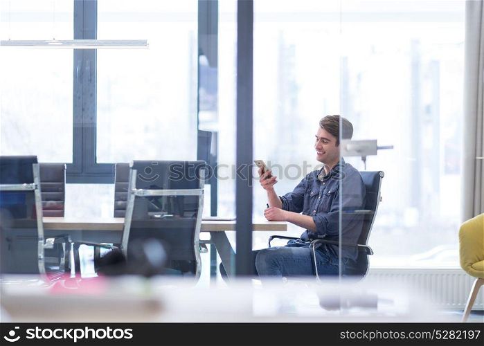 Young casual businessman using smartphone in the startup office