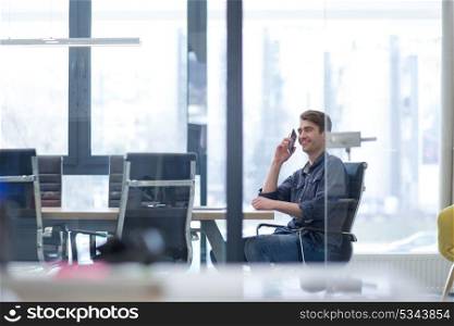 Young casual businessman using smartphone in the startup office