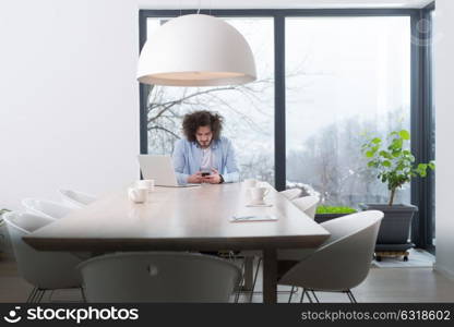 Young casual businessman using smartphone in the startup office