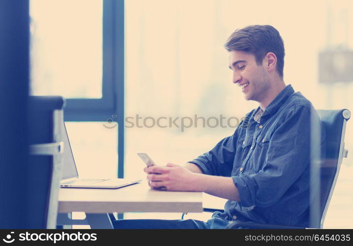 Young casual businessman using smartphone in the startup office