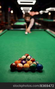 Young casual man aiming with billiards cue on colorful balls to start the game, selective focus. Young man aiming with billiards cue