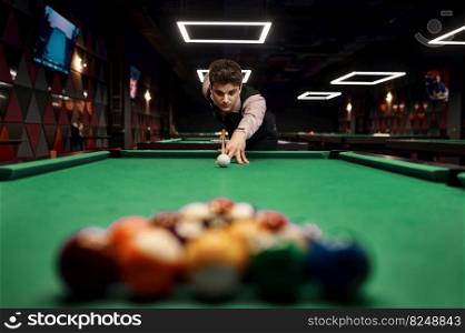 Young casual man aiming with billiards cue on colorful balls to start the game. Young man aiming with billiards cue