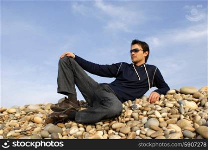 young casual man at the beach stones