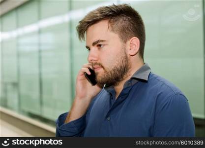 young casual man on the phone inside an office building