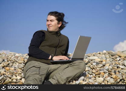 young casual man with laptop at the beach