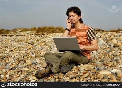 young casual man with laptop at the beach