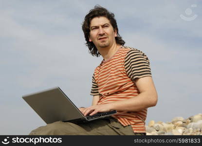 young casual man with laptop at the beach