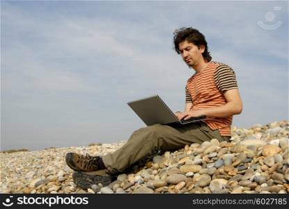 young casual man with laptop at the beach