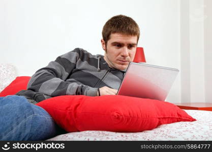 young casual man working with computer in bed