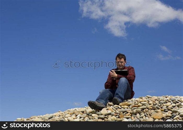 Young casual man working with touch pad at the beach