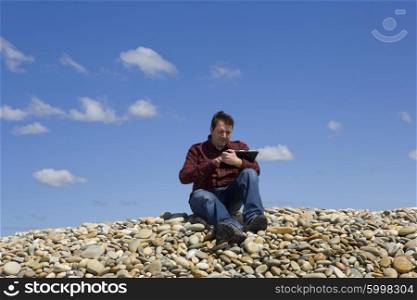 Young casual man working with touch pad at the beach