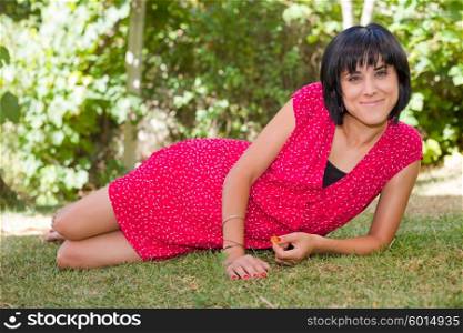 young casual woman posing laid, smiling at the camera, outdoors