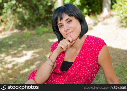 young casual woman posing seated, smiling at the camera, outdoors