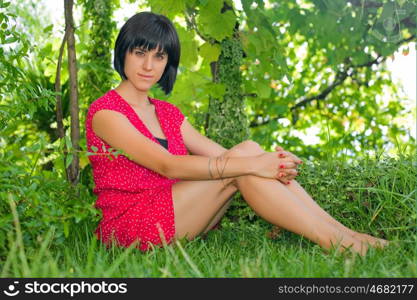 young casual woman posing seated, smiling at the camera, outdoors