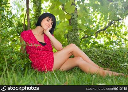 young casual woman posing seated, smiling at the camera, outdoors