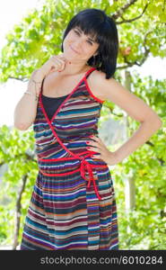 young casual woman posing seated, smiling at the camera, outdoors