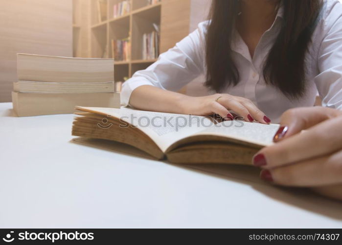 young casual woman reading a book at a library