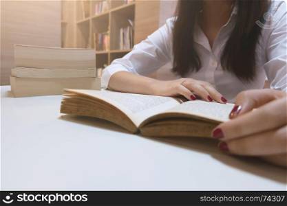 young casual woman reading a book at a library