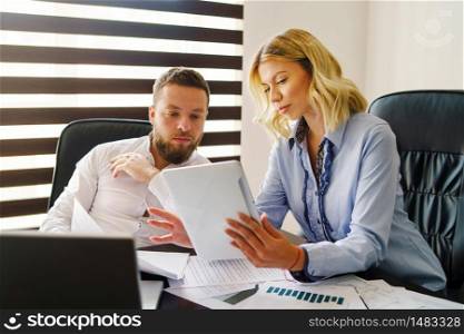 Young caucasian adult man and woman at office looking digital tablet