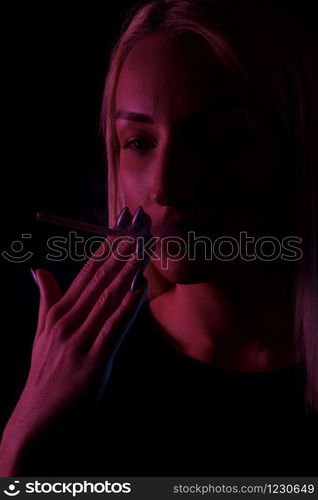 young Caucasian beautiful blonde woman Smoking. close-up portrait in neon light