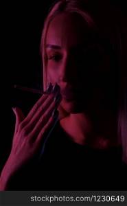 young Caucasian beautiful blonde woman Smoking. close-up portrait in neon light