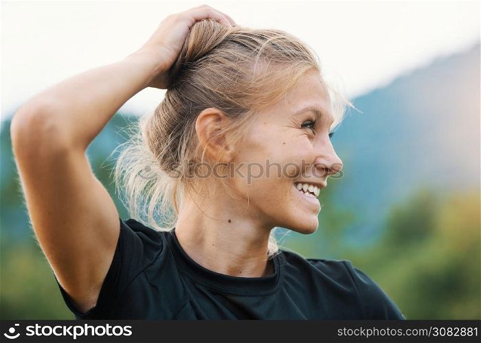 Young Caucasian blond girl is holding her hair with hand