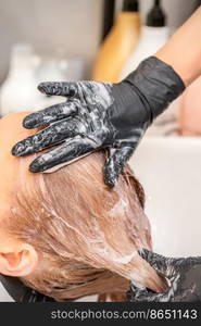 Young caucasian blonde woman having hair washed in the sink at a beauty salon. Young caucasian blonde woman having hair washed in the sink at a beauty salon.