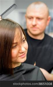 Young caucasian brunette woman having her hairstyling by a male hairdresser at a parlor. Young caucasian brunette woman having her hairstyling by a male hairdresser at a parlor.