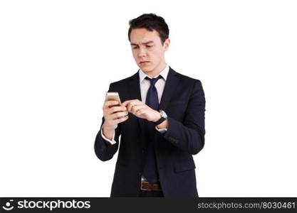 Young Caucasian business man frowning looking at mobile phone. A young Caucasian business man is frowning holding a moble phone. He is operating the smart phone with fingers on the screen.