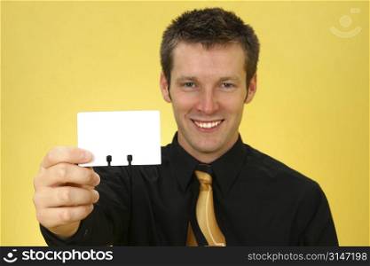 Young Caucasian business man holding up a rolodex card. Focus on card.