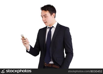 Young Caucasian business man looking at mobile phone smiling. A young Caucasian business man is holding a mobile phone smiling. His hand is on the screen operating the smart phone. He is looking at the smart phone with one hand in the pocket.