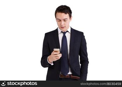 Young Caucasian business man looking at mobile phone smiling. A young Caucasian business man is holding a mobile phone smiling. His hand is on the screen operating the smart phone. He is looking at the smart phone with one hand in the pocket.