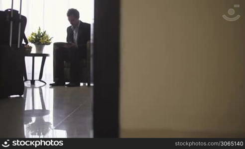 Young caucasian businessman typing on tablet pc in hotel room during business travel. Dolly shot