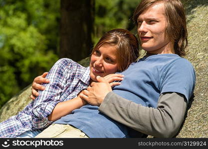 Young Caucasian couple enjoying sunshine lying on rock