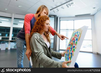 Young caucasian couple standing in a gallery and contemplating artwork. Young caucasian couple standing in a gallery and contemplating abstract artwork