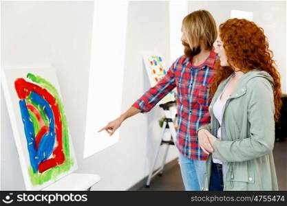 Young caucasian couple standing in a gallery and contemplating artwork. Young caucasian couple standing in a gallery and contemplating abstract artwork