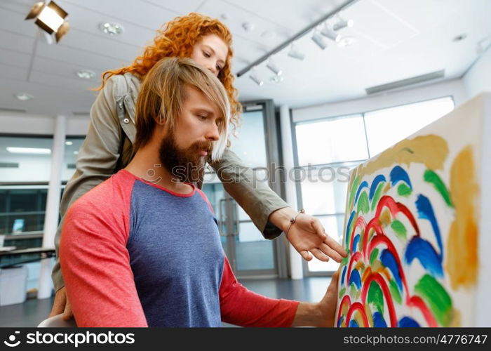 Young caucasian couple standing in a gallery and contemplating artwork. Young caucasian couple standing in a gallery and contemplating abstract artwork