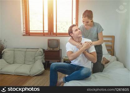 Young caucasian couple with happy moment on bed in bedroom,Young woman embracing piggyback man with love.Valentine day concept with copy space.