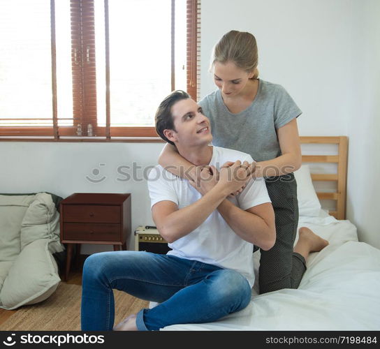 Young caucasian couple woman hug man back on bed with love on bed in bedroom at home.. asian woman hug man from back on bed at home