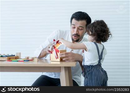 Young Caucasian father with beard and little cute daughter are opening gift box together with surprise face at living room at home. White background