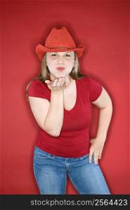 Young Caucasian female adult blowing kiss wearing red cowboy hat.