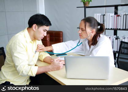 Young Caucasian Female psychiatrist is specialist in psychiatry is Maintaining with Stethoscope on back of asian male Patient with depression in Clinical treatment for emotional symptoms.