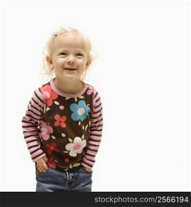 Young Caucasian female toddler with hands in her pockets and laughing.