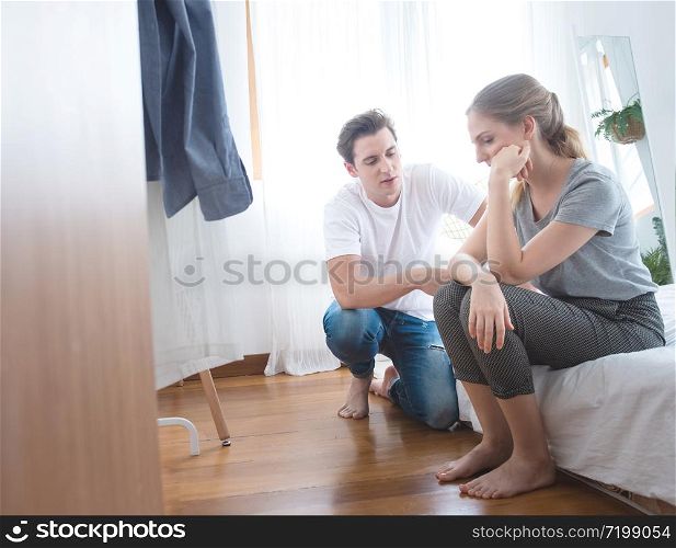 Young caucasian man comforting sad woman and sit on begin bedroom
