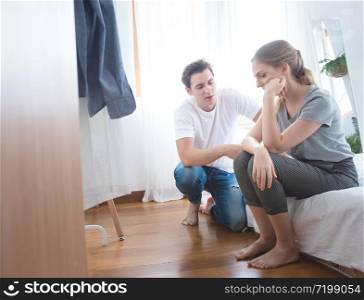 Young caucasian man comforting sad woman and sit on begin bedroom