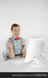 Young Caucasian man looking at computer monitor smiling and making excited gesture.