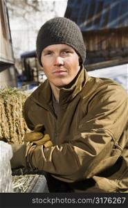 Young Caucasian man wearing hat outdoors in rural country looking at viewer.