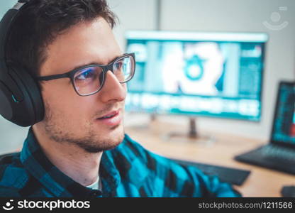 Young Caucasian man with headphones sitting on his workplace, entrepreneur